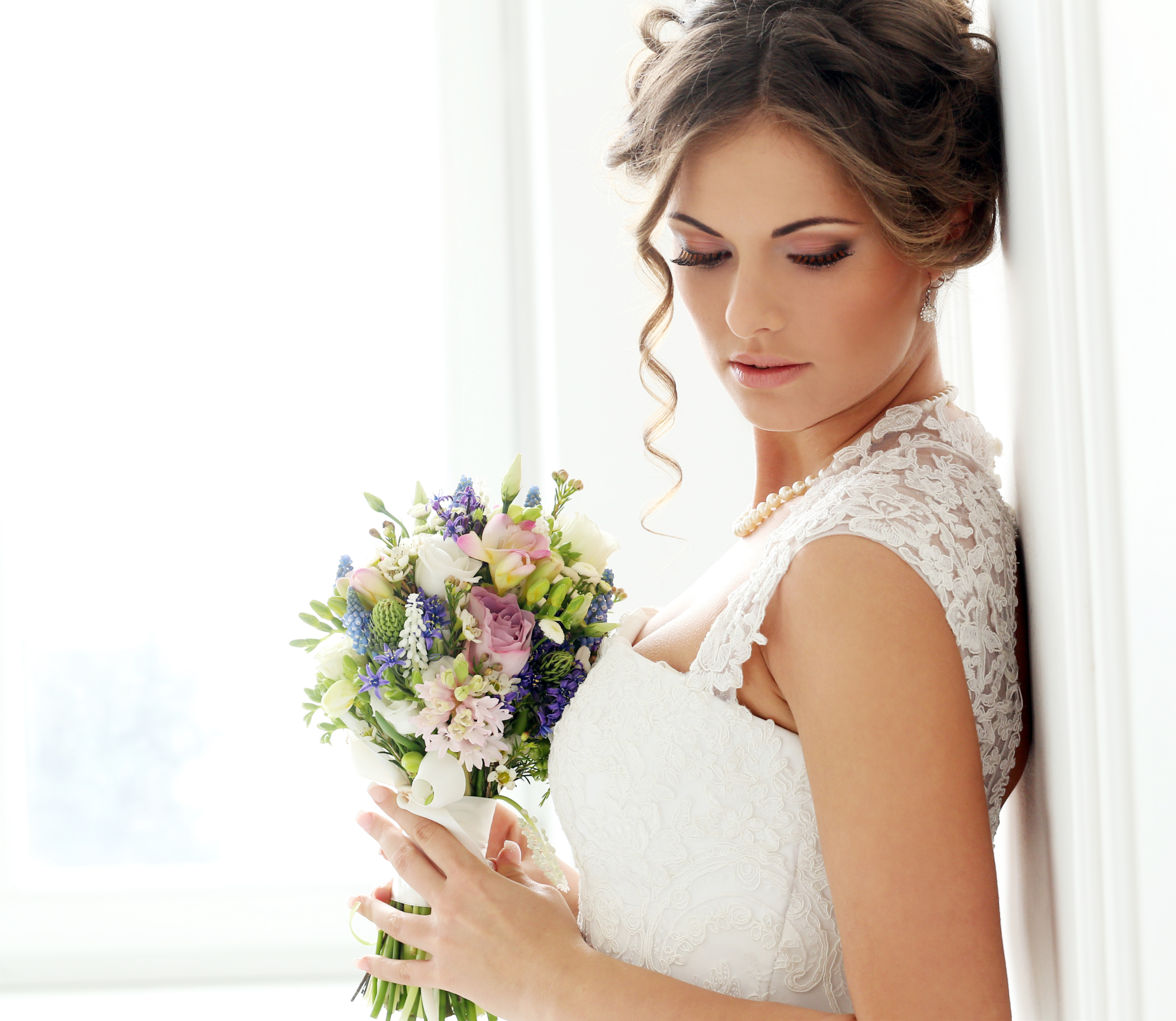 Sposa con bouquet di fiori appoggiata al muro